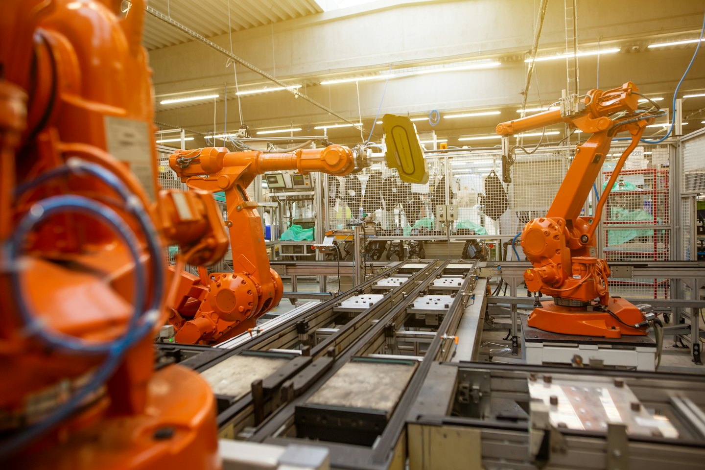 Roboterarme montieren Bauteile auf einem hell erleuchteten Fabrikboden.